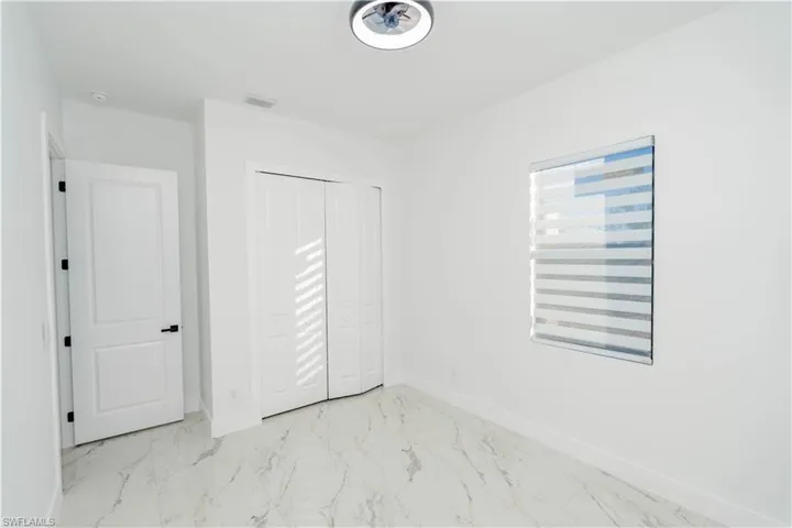 Unfurnished bedroom with light marble finish flooring and a closet