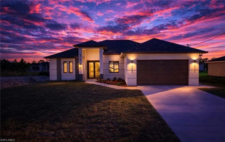 View of front of property with stucco siding, driveway, a front lawn, and an attached garage
