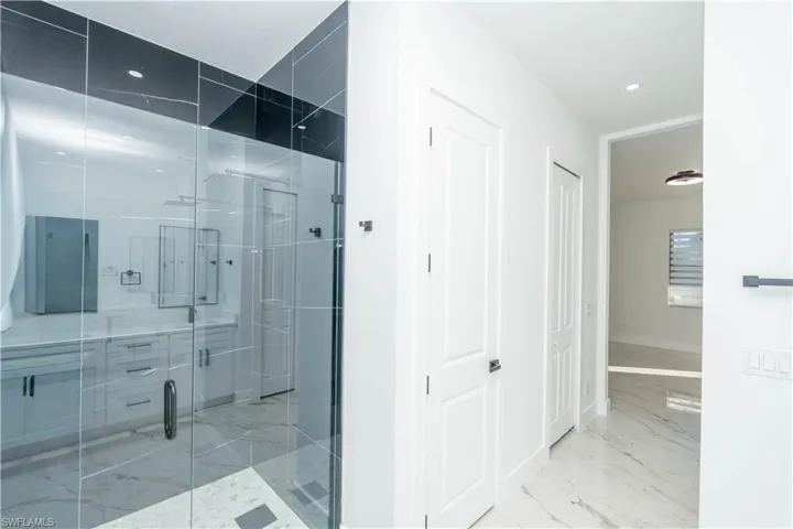 Bathroom featuring light marble finish flooring, a stall shower, recessed lighting, and a closet