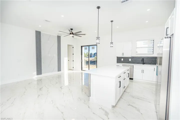 Kitchen with white cabinets, open floor plan, stainless steel appliances, hanging light fixtures, and recessed lighting