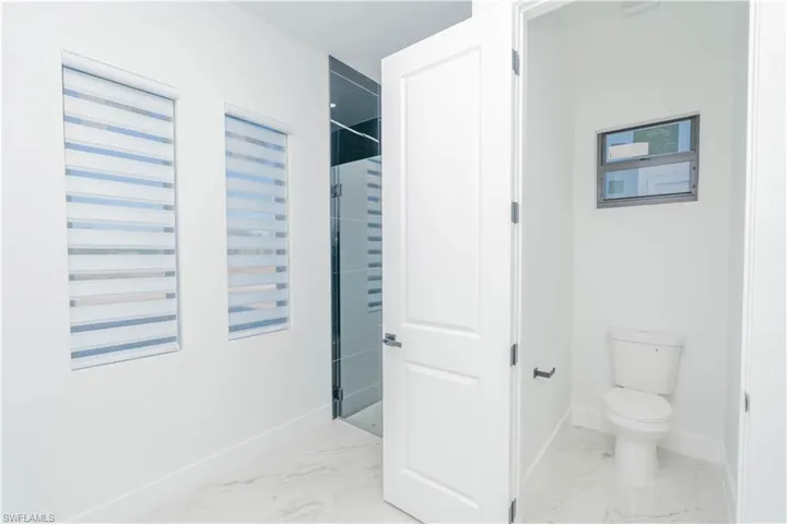 Full bath featuring a shower and light marble finish flooring