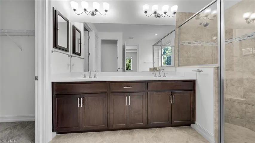 Bathroom featuring a stall shower, double vanity, a spacious closet, and recessed lighting