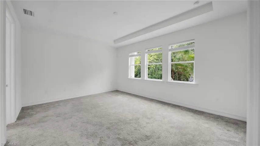 Carpeted Master Bedroom with a tray ceiling and Lots of Natural Light
