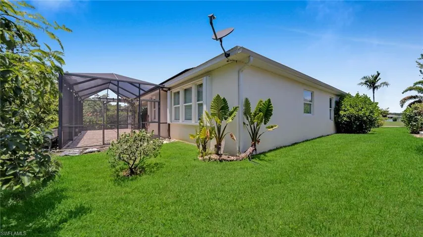 Back of property featuring  Huge screened paver lanai, side yard, hurricane accordian shutters