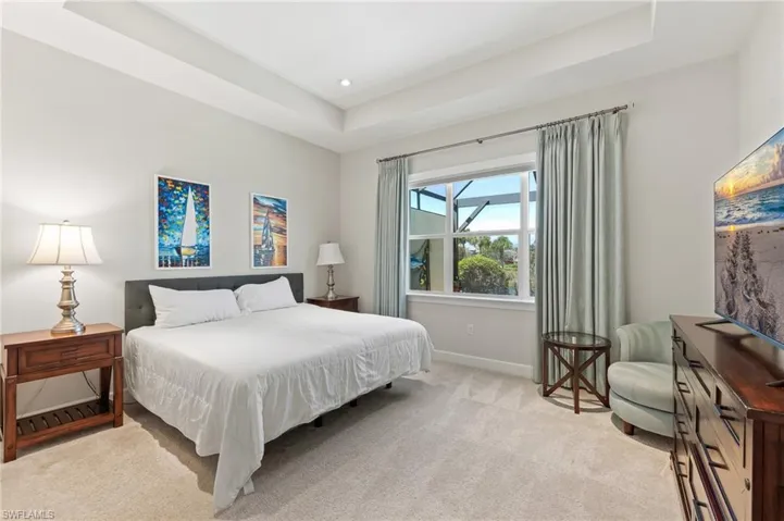 Primary Suite with a tray ceiling and light colored carpet