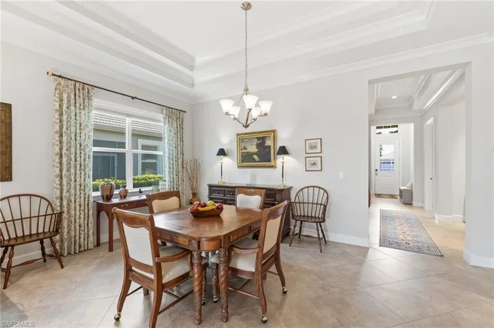 Dining room with suspended lighting, a raised ceiling, and crown molding