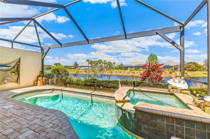 Relaxing pool / spa with a sunroom, a lanai, a patio area, and a water view