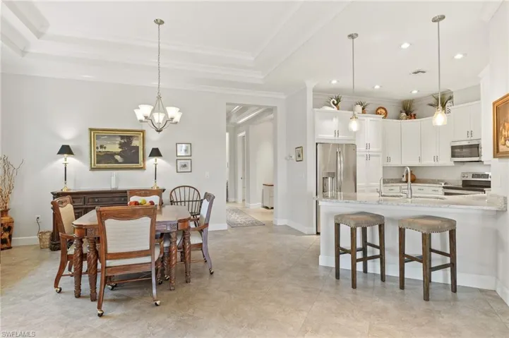 Dining space featuring hanging lights, ornamental molding, and a tray ceiling