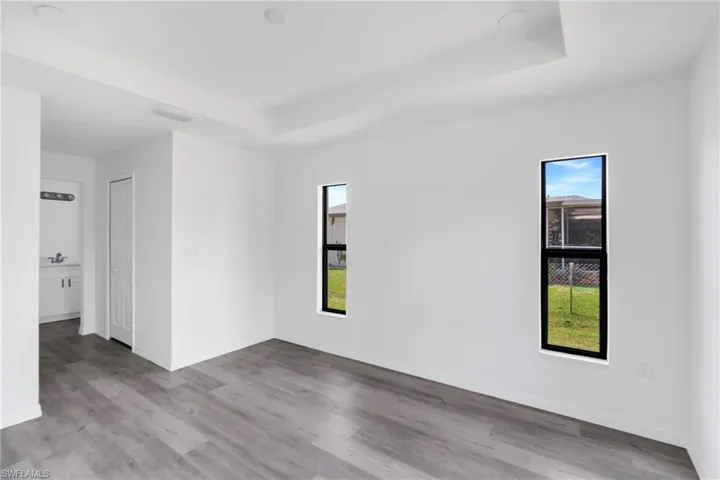 Spare room featuring a raised ceiling, plenty of natural light, light wood-type flooring, and recessed lighting