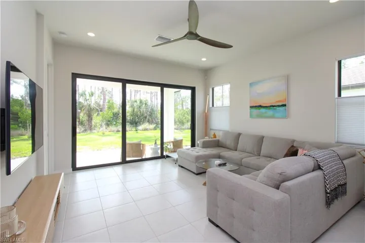 Living room featuring ceiling fan, a wealth of natural light, and light tile patterned floors