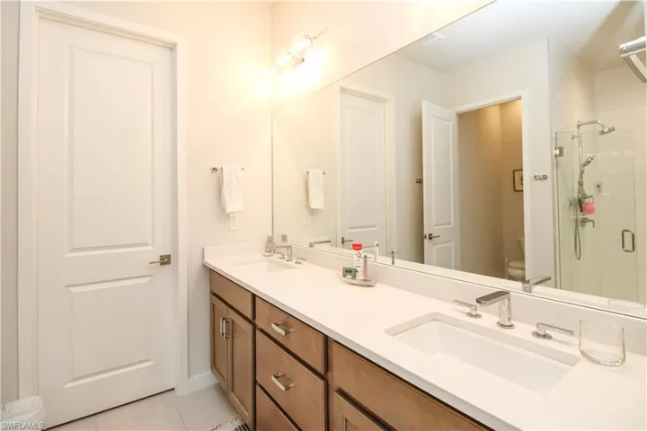 Bathroom with toilet, a shower with door, tile patterned flooring, and vanity
