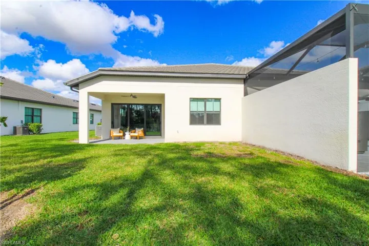 Rear view of property featuring glass enclosure, a yard, ceiling fan, a patio area, and central air condition unit