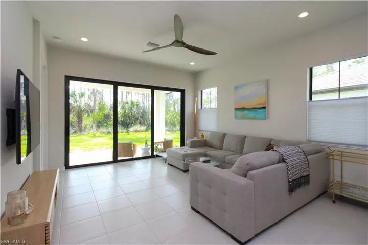 Tiled living room with a healthy amount of sunlight and ceiling fan