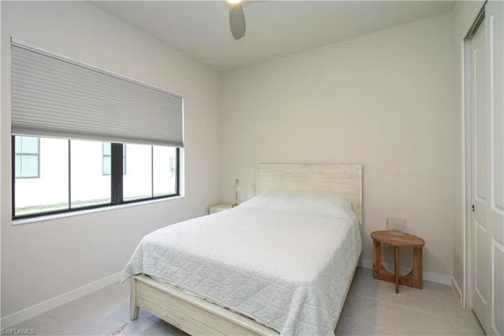 Bedroom with light tile patterned flooring, a closet, and ceiling fan