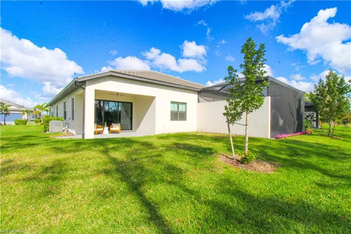Rear view of property with a yard, a patio, a lanai, and central AC