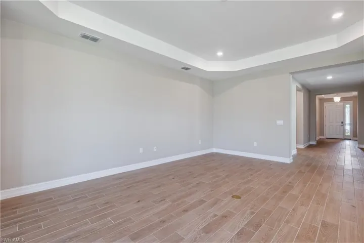 Spare room featuring light wood-type flooring and a raised ceiling