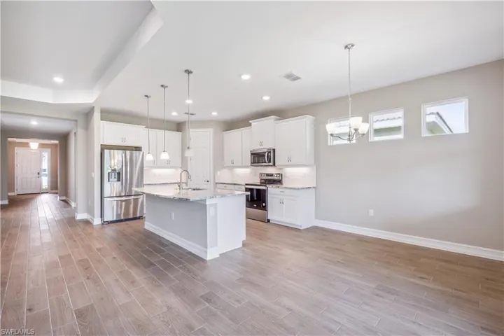 Kitchen featuring stainless steel appliances, light wood-type flooring, sink, and white cabinetry