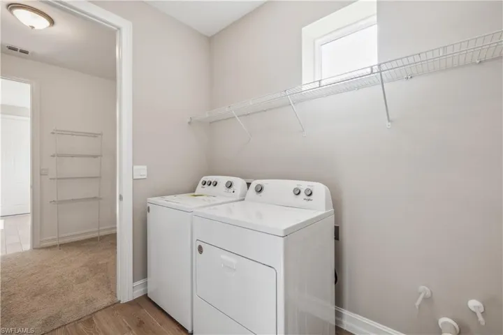 Laundry room with washing machine and clothes dryer and light hardwood / wood-style flooring