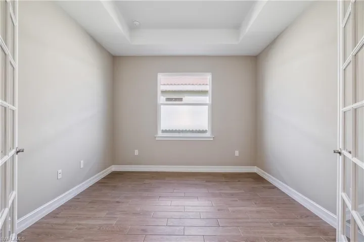 Empty room with a tray ceiling and light hardwood / wood-style floors