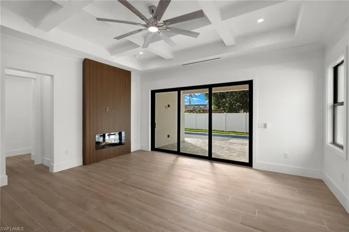 Spare room featuring plenty of natural light, ceiling fan, light wood-type flooring, and coffered ceiling