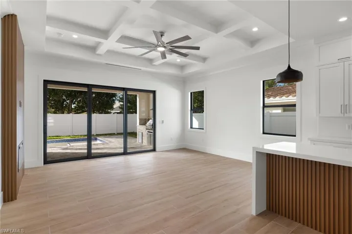 Unfurnished living room featuring coffered ceiling, plenty of natural light, and light hardwood / wood-style flooring