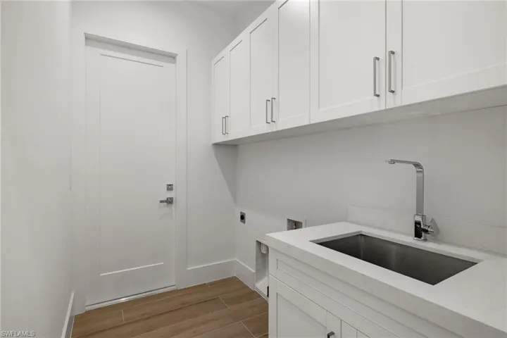 Laundry room featuring hardwood / wood-style flooring, electric dryer hookup, cabinets, and sink