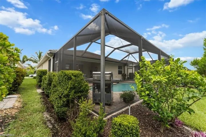 Back of house with an outdoor pool and a lanai