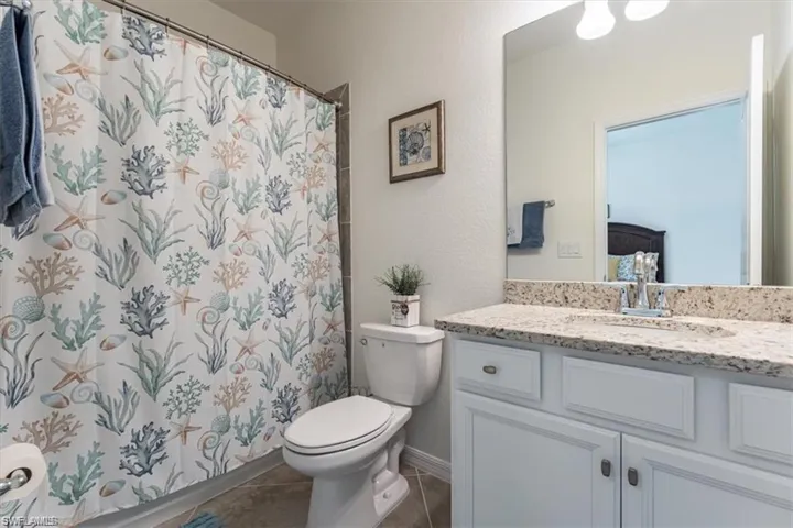 Full bathroom with vanity, tile patterned floors, and curtained shower