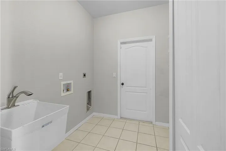Laundry room with tub featuring hookup for a washing machine, light tile patterned floors, and electric dryer hookup.  LOADS of additional storage!