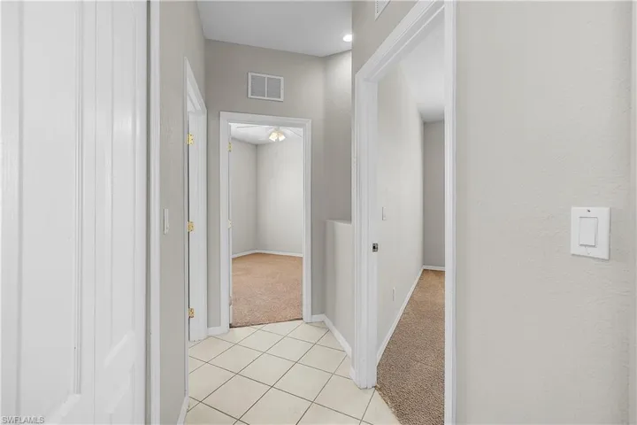 Hall with linen storage, light tile patterned floors