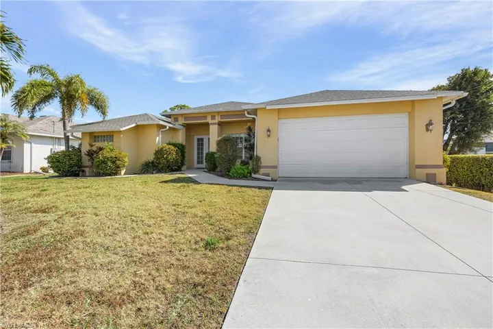View of front facade featuring a front yard, stucco siding, concrete driveway, and a garage