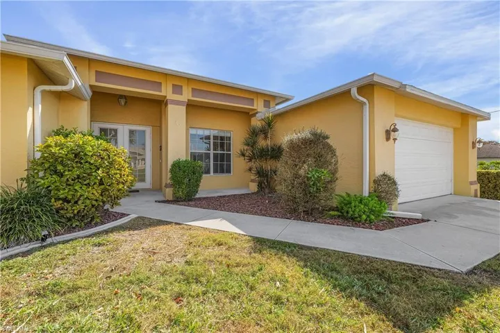 View of front of home featuring stucco siding, a garage, a front yard, and concrete driveway