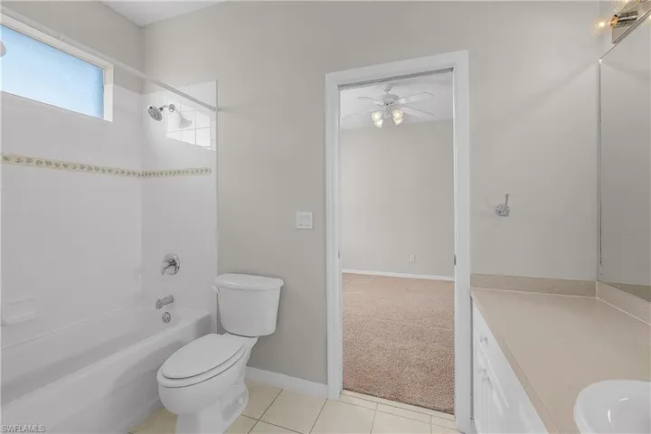 Jack & Jill Bathroom with vanity, shower / tub combination, light tile patterned floors.