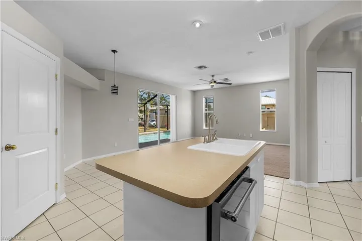 Open Kitchen/Familyroom featuring an island with sink, light countertops, a ceiling fan, and Sliders to Pool