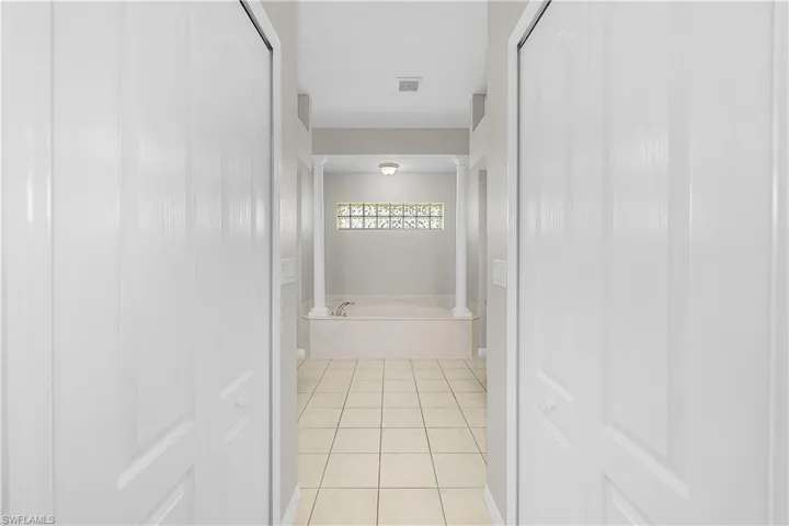 Bathroom with a Soaking tub and light tile patterned floors. His & Hers Closets