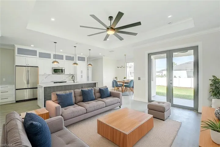 Living area featuring ornamental molding, a raised ceiling, french doors, recessed lighting, and a ceiling fan. Staged picture
