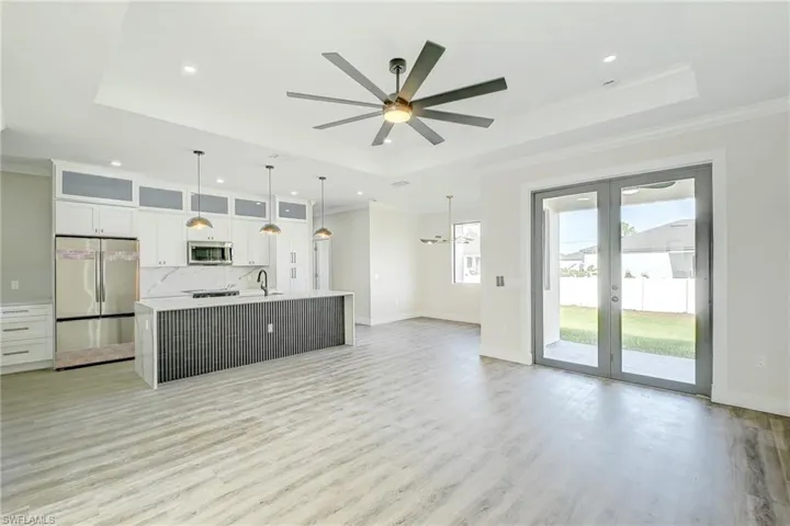 Kitchen with glass insert cabinets, appliances with stainless steel finishes, white cabinets, an island with sink, and crown molding