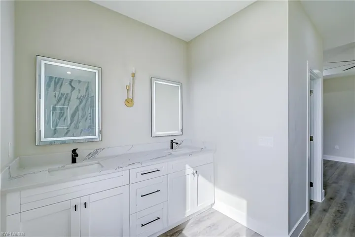 Full bathroom with double vanity and light wood-style floors