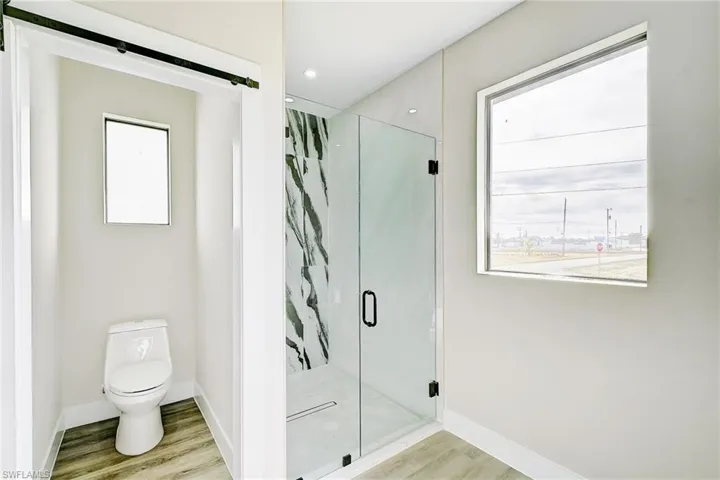 Full bath featuring a marble finish shower, light wood-style flooring, and recessed lighting