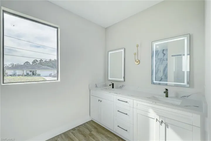 Full bath featuring double vanity and light wood-type flooring