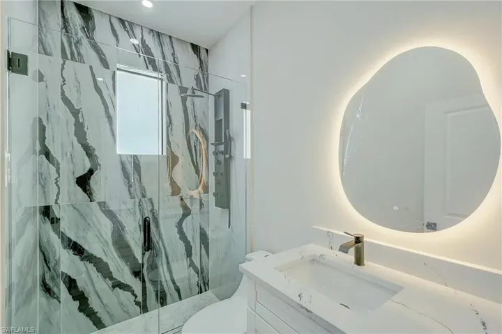 Full bath with a marble finish shower and vanity