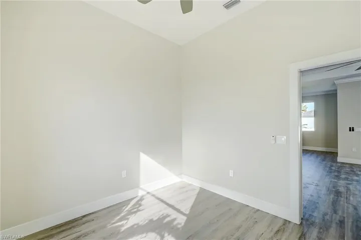 Unfurnished room featuring light wood-type flooring, ceiling fan, and crown molding