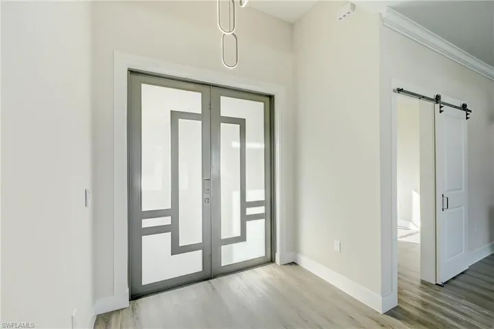 Foyer featuring a barn door, light wood finished floors, and crown molding