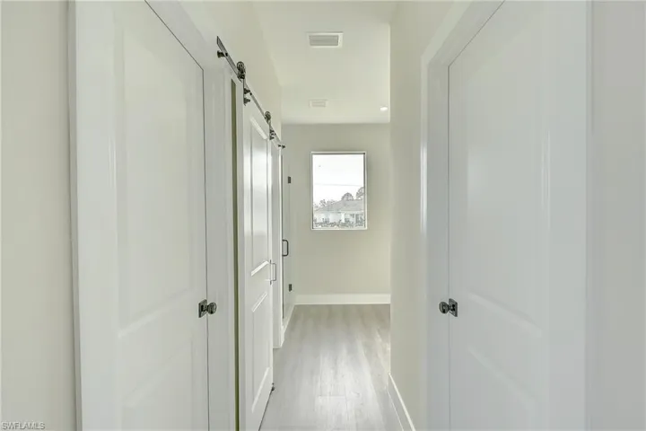 Hallway featuring light wood-type flooring and a barn door