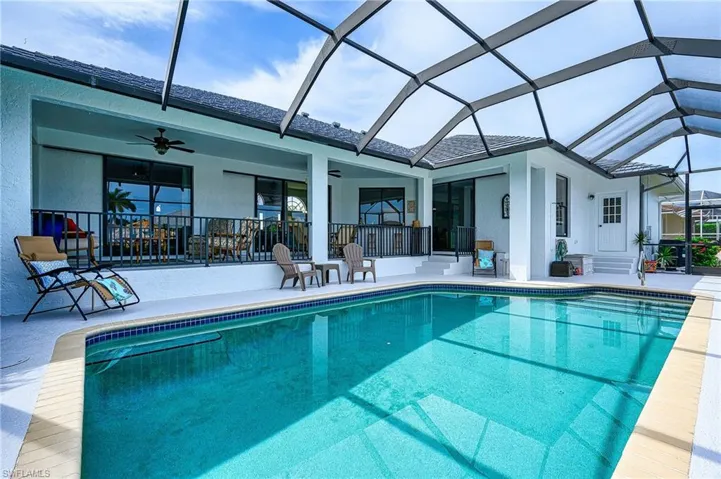 View of swimming pool with a patio area, ceiling fan, and glass enclosure