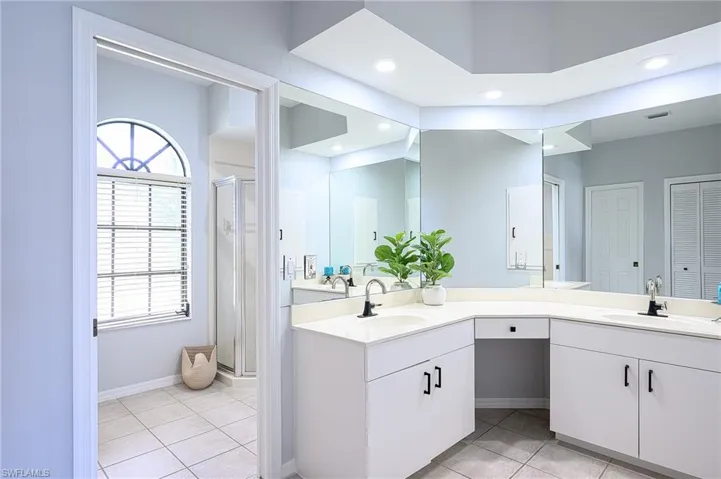 Bathroom featuring tile patterned flooring, double vanity, and a shower with shower door