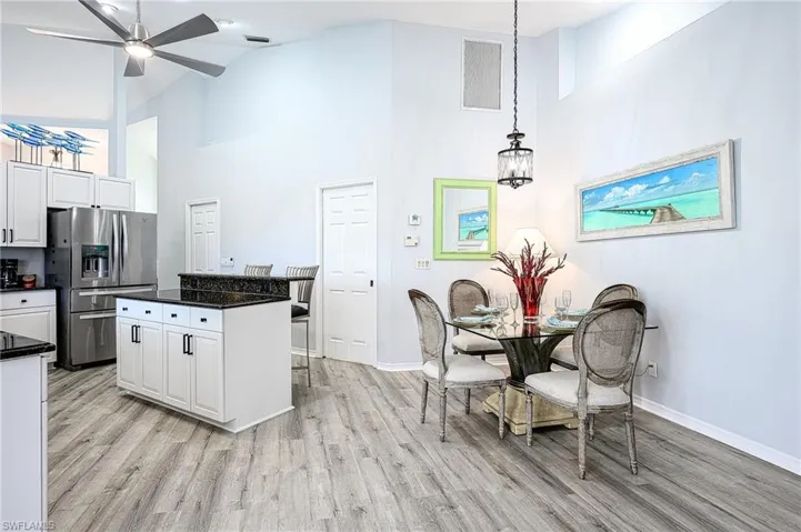 Kitchen with white cabinets, light wood-type flooring, and a high ceiling