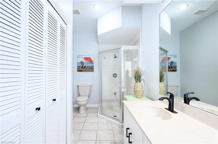 Bathroom with walk in shower, tile patterned floors, toilet, and vanity