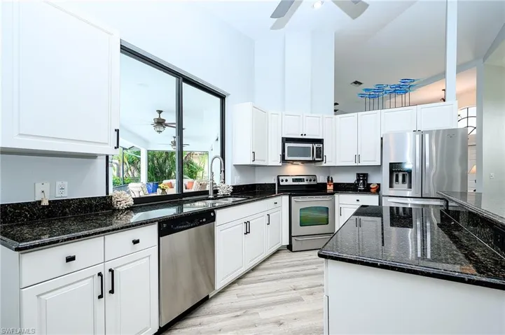 Kitchen with white cabinetry, light hardwood / wood-style flooring, ceiling fan, appliances with stainless steel finishes, and sink