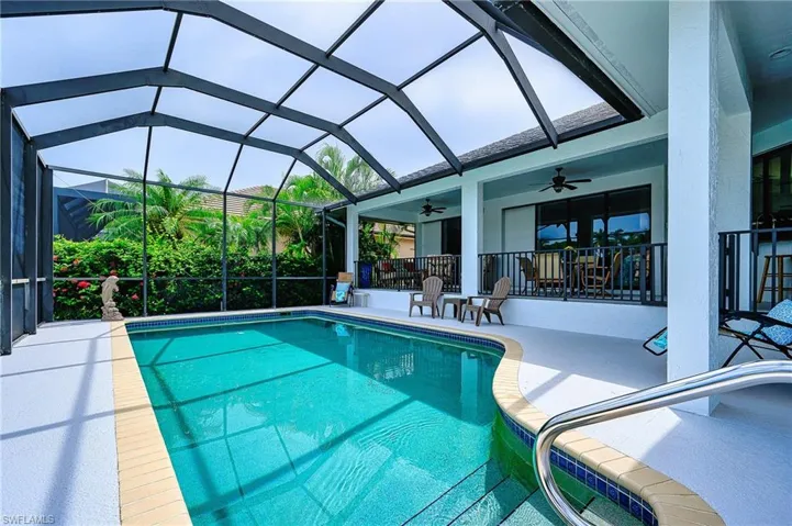 View of swimming pool with glass enclosure, a patio area, and ceiling fan